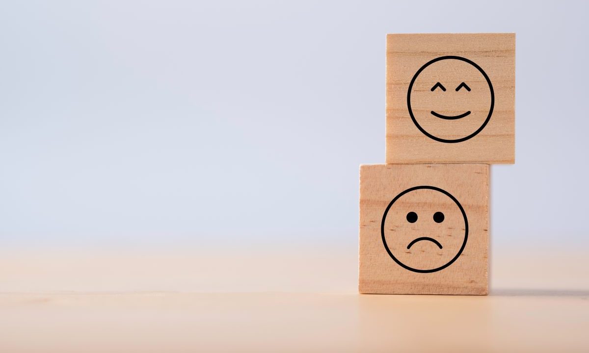 Due emozioni di felicità e tristezza che vengono stampate su un cubo di legno per indicare pro e contro di valutazione casa online