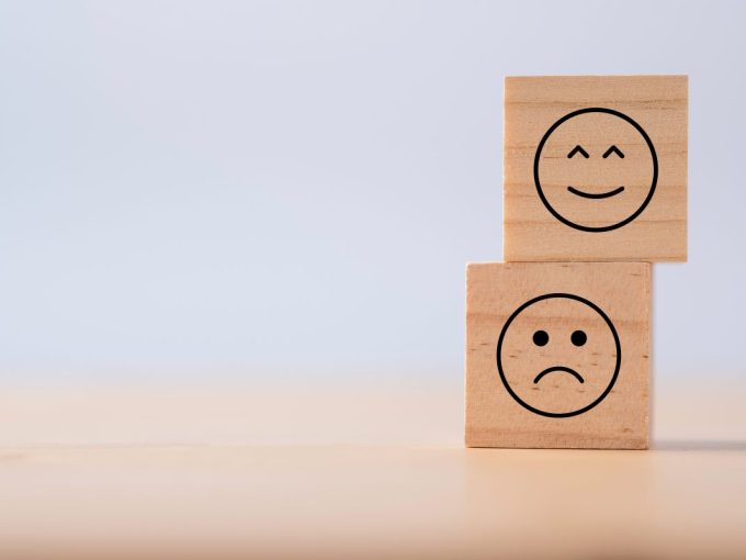 Due emozioni di felicità e tristezza che vengono stampate su un cubo di legno per indicare pro e contro di valutazione casa online